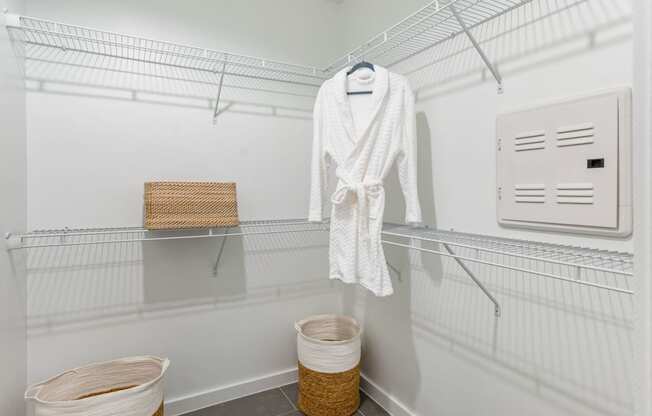 a walk in closet with wire shelves and a white robe and baskets