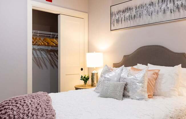 A bedroom with a bed, pillows, and a painting on the wall.