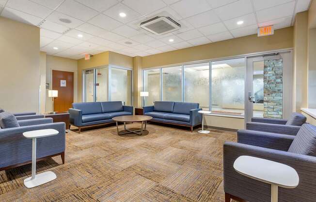 A waiting room with blue couches and chairs.
