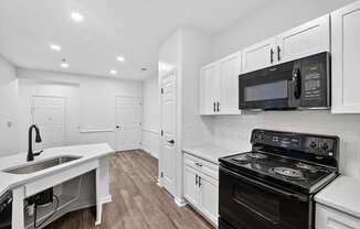 Renovated kitchen with white cabinets and black appliances next to dining room