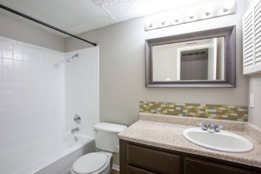 A bathroom with a toilet, sink, and mirror.