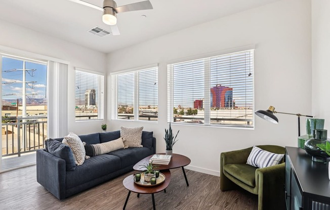 A living room with a couch, a chair, a table, and a fan.