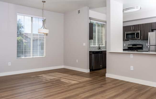 an empty kitchen and living room with wood flooring and a window