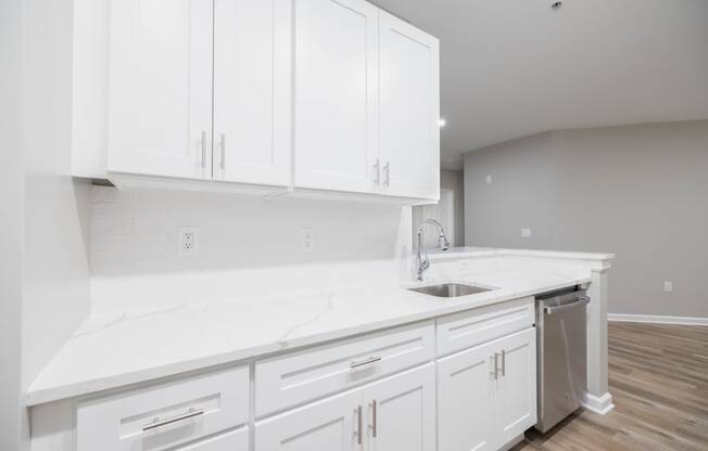 a white kitchen with white cabinets and a stainless steel sink