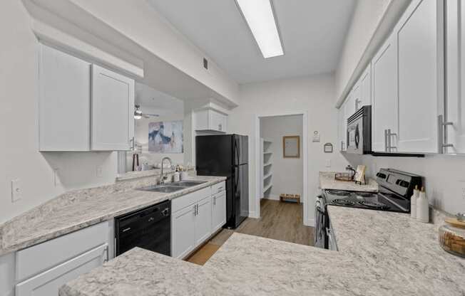 a large kitchen with marble counter tops and white cabinets