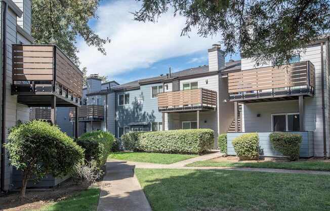 A green space with apartment buildings and a sidewalk at Sierra Glen Apartments, California, 95621