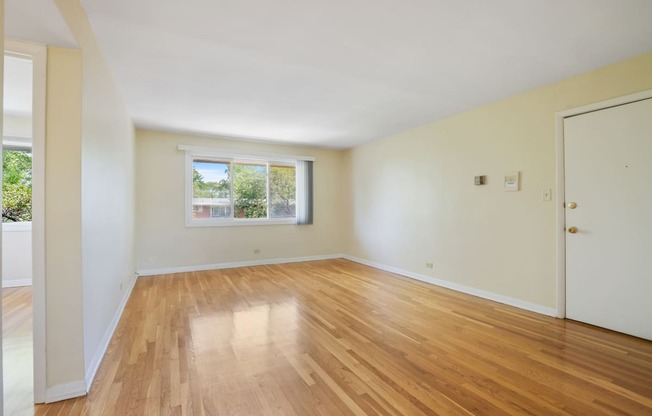 an empty living room with wooden floors and a window