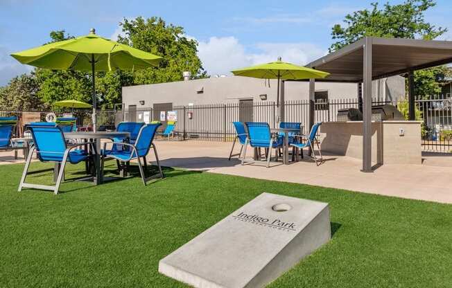 Outdoor Corn Hole and BBQ Area with Covered Patio Furniture at Indigo Park Apartments in Albuquerque, NM.