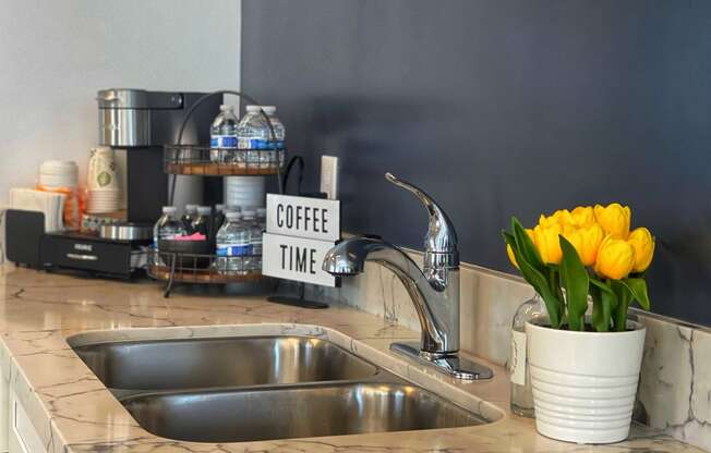 a kitchen sink with a yellow flower in a white vase