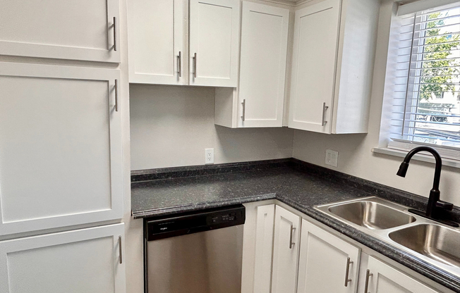 Chic kitchen with sleek stainless steel appliances, elegant white cabinets, and a modern double sink with a polished countertop.