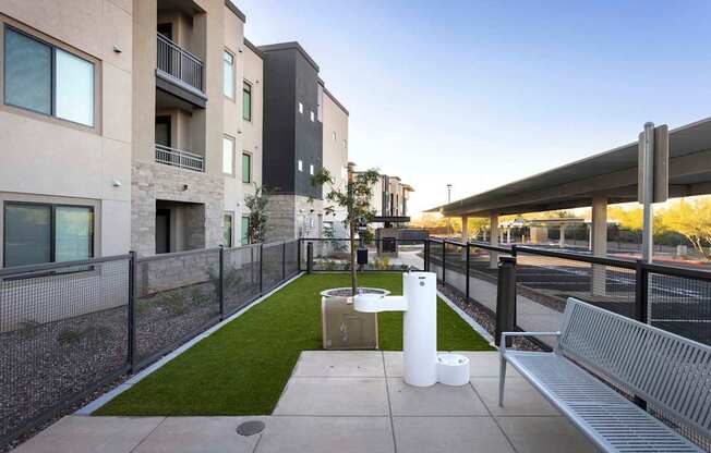 A modern outdoor seating area with a bench and a table with two white cylindrical objects on it.