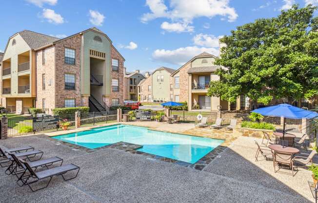 Community pool with lounge chairs surrounded by apartments at Bandera Crossing apartments in San Antonio, TX