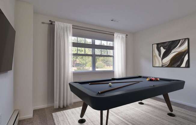A pool table in a room with a window and a painting on the wall.