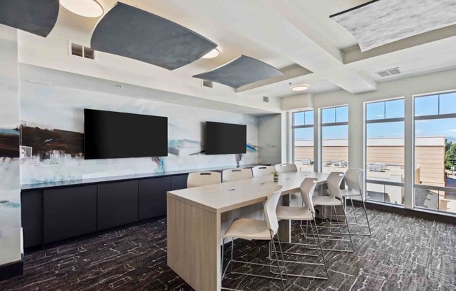 a conference room with a long table and chairs and televisions