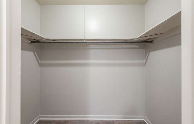 A white closet with a shelf and a hanging rod.