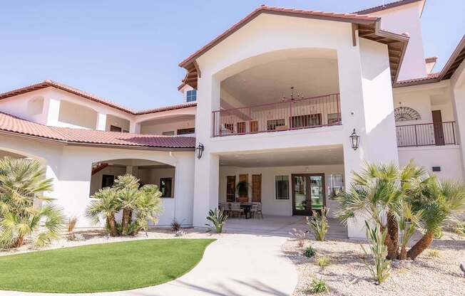A white house with a red tile roof and a balcony.