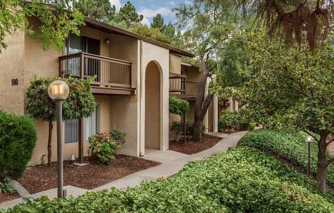 A building with a balcony and a tree in front of it.
