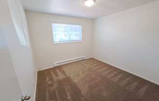 a small bedroom with a small window and a carpeted floor