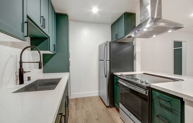 a kitchen with green and white cabinets and a stainless steel refrigerator