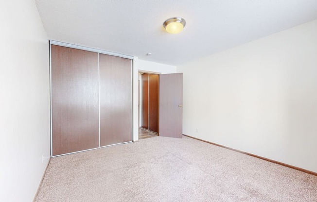 a bedroom with white walls and a sliding door to a closet