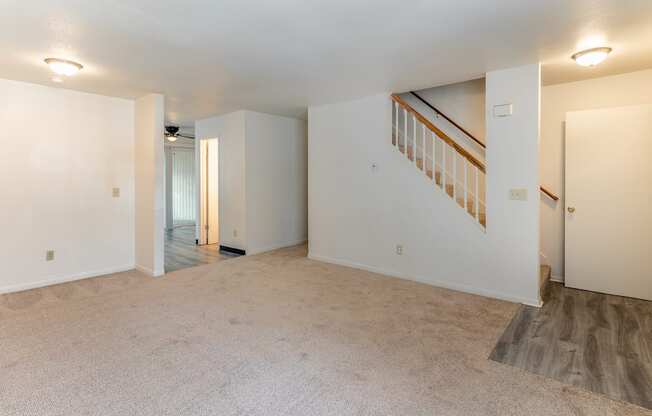 the living room and dining room of an empty home with white walls and carpeting