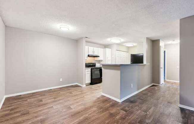 an empty living room and kitchen with a wood floor