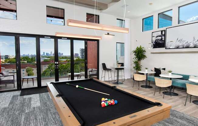 a billiards table in a clubhouse with a view of a patio and windows