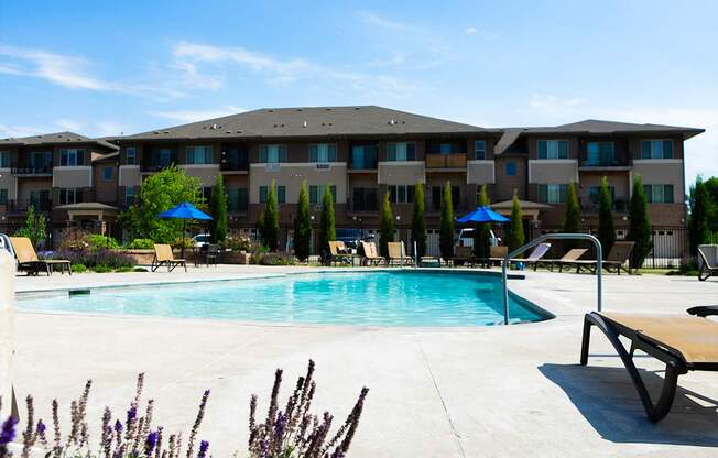 A pool area in front of a large apartment complex.