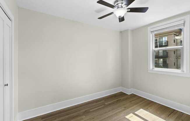 a bedroom with hardwood floors, a large window, and a ceiling fan with light at Stockbridge Apartment Homes, Seattle