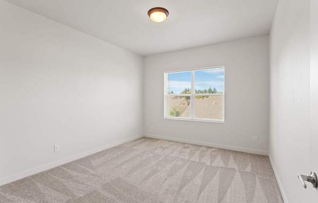 A room with a carpeted floor and a window showing a view of the outdoors.