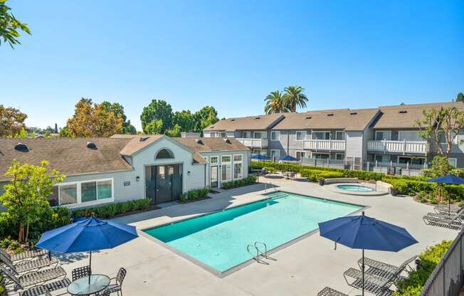 a swimming pool with umbrellas and apartments in the background