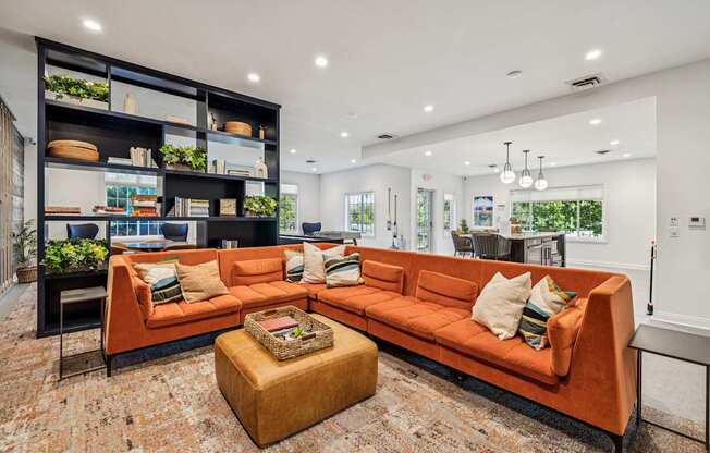 A living room with a large orange sofa and a coffee table in front of a bookshelf.