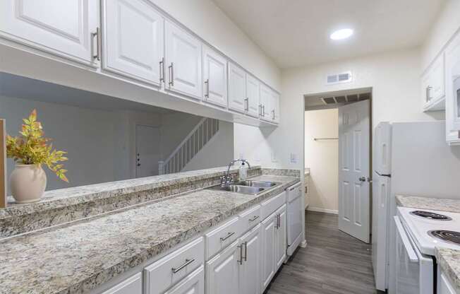 Kitchen with white cabinets and white appliances and large pass-through window in a 2 bedroom, 1.5 bath 1084 sq ft, 2-floor townhome at The Biltmore Apartments located in the Vickery Midtown neighborhood of Dallas, TX.