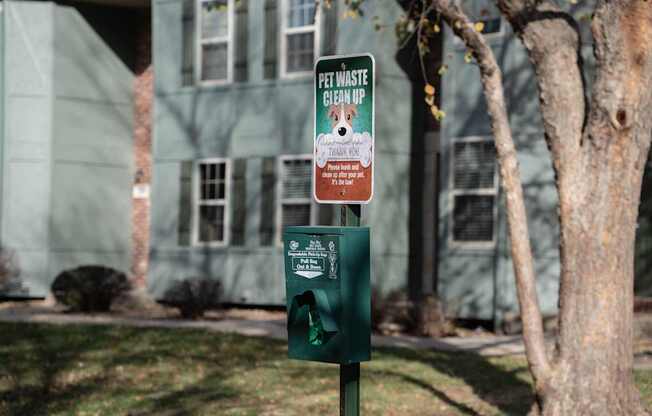 A green trash can with a sign that says "Pet Waste Pick Up" on it.