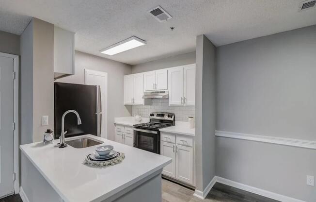 a white kitchen with a sink and a refrigerator at The Sapphire, Decatur