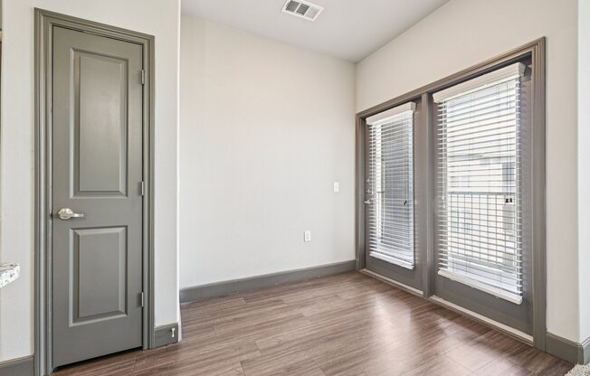 A room with a grey door and a window with blinds.