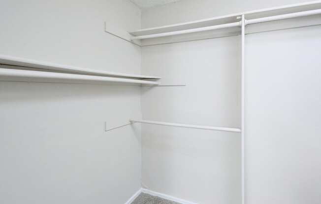 a walk in closet with white walls and white shelves and a white