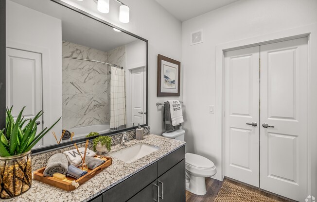 A bathroom with a marble countertop and a wooden tray with toiletries on it. at Aurora Watson Branch, Mansfield, TX