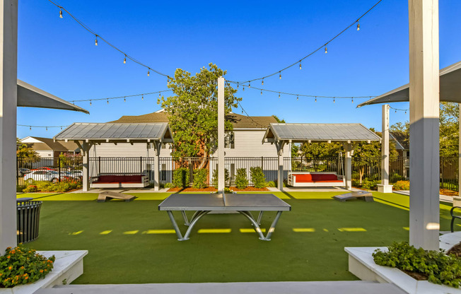 a ping pong table sits in the middle of a courtyard with picnic tables at Crossgates Apartment Homes, Starkville, MS 39759