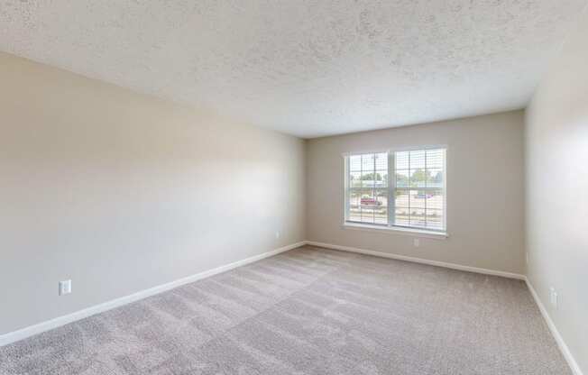 an empty living room with a window and white walls