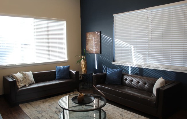 a living room with leather couches and a glass table