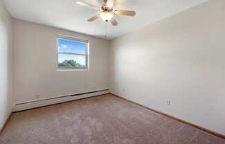 an empty room with a ceiling fan and a window