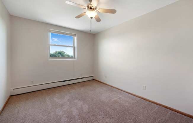 an empty room with a ceiling fan and a window