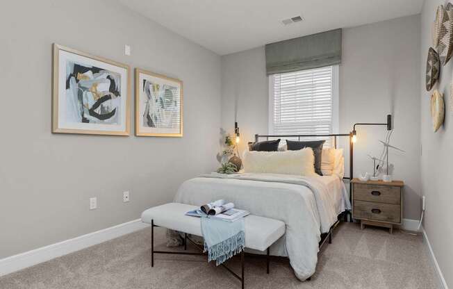 A bedroom with a bed, nightstand, and two framed pictures on the wall.