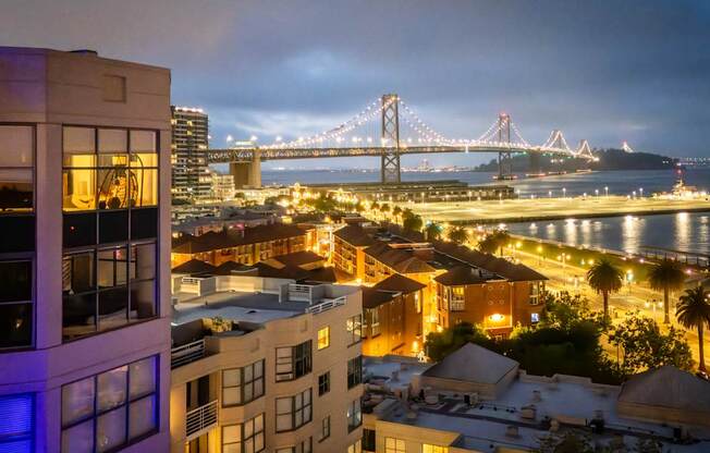 A cityscape at night with a bridge in the background.