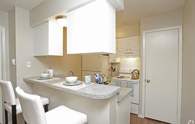 a kitchen and dining area with white cabinets and a granite counter top