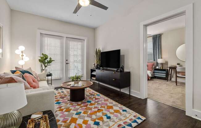 A living room with a white couch and a colorful rug.