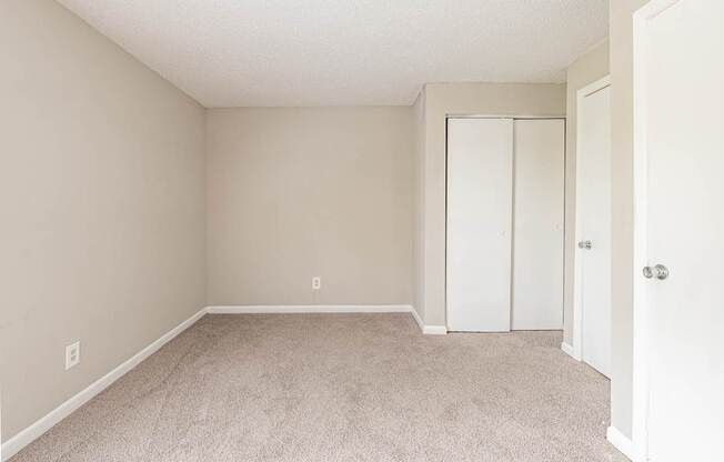 A room with a white door and carpeted floor.