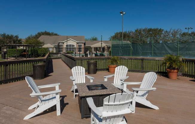 a patio with white chairs and a fire pit