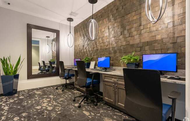 A room with a brick wall and a row of computer monitors.